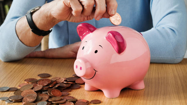Senior woman inserting coins into piggybank 